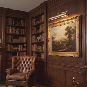 May include: A study room featuring dark wood paneled walls, built-in bookshelves filled with leather-bound books, a tufted brown leather armchair, a landscape painting in a gold frame with a brass picture light, and a globe on a stand.