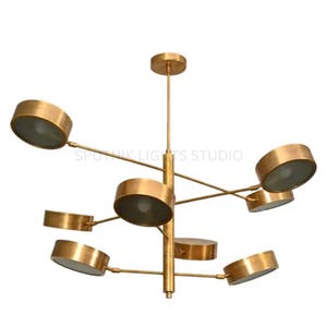May include: A contemporary gold chandelier featuring multiple circular light fixtures. The central vertical rod supports horizontal arms, each holding a circular light. The lights have a gold finish and a frosted glass cover. A stylish lighting fixture.
