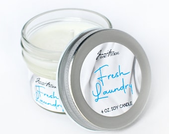 May include: A 4 ounce soy candle in a glass jar with a silver lid. The lid has a white label with a blue and white design and the text "Fresh Laundry".