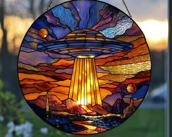 以下が含まれることがあります： 風景の上にUFOを描いた丸いステンドグラスパネル。このアートワークは、空飛ぶ円盤、光線、天体の詳細なデザインを備えた、青とオレンジの配色が特徴です。パネルはチェーンで吊り下げられています。