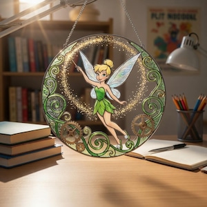 May include: Round stained glass window featuring Tinkerbell with a wand, surrounded by green vines and gears. The fairy is wearing a green dress and has large, iridescent wings. The window is hanging from a chain, with a blurred background of a desk and bookshelves.