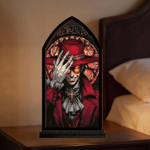 May include: A gothic stained glass panel depicting a smiling character in a red hat and coat, with orange glasses and a white glove. The artwork is set in a black frame, resting on a dark wooden surface.