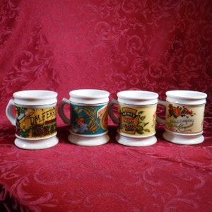 May include: Four white ceramic mugs with gold trim and vintage advertisements. The mugs feature images of a boy, a seed packet, pickles, and a vegetable compound. The mugs are arranged in a row on a red background.