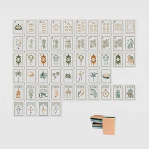 May include: A set of rectangular mahjong tiles featuring various illustrations including numbers one through nine, botanical motifs, animals, lanterns, and joker tiles. Four tiles at the bottom display the letters N, E, W, and S. A small stack of tiles sits separately.