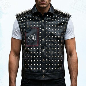 May include: Black leather vest with silver stud and spike embellishments. The vest features a collared neckline, button-up front, and a patch with a skull design. The vest is worn over a white t-shirt.