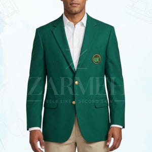 May include: A dark green blazer with gold buttons and a small emblem on the chest. The blazer is worn over a white dress shirt. The text "ZARMEE" and "FEELS LIKE SECOND SKIN" is visible on the blazer.
