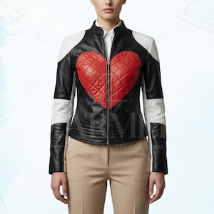 Puede incluir: Chaqueta de cuero negra con un gran corazón rojo acolchado en la parte delantera. La chaqueta tiene paneles blancos en los hombros y las mangas. Cuenta con cierre de cremallera y cuello alto.