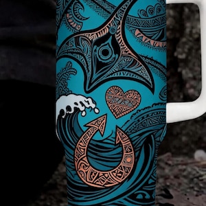 May include: A teal travel mug with a white handle and lid. The mug features a detailed design of a manta ray, waves, and other Polynesian-inspired symbols in black and orange. The background is a teal colour.