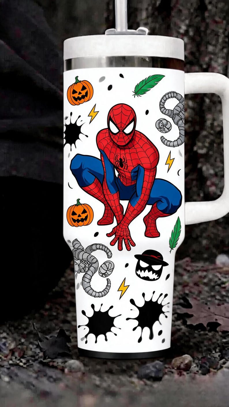 May include: A white stainless steel tumbler with a handle and lid featuring a graphic of Spider-Man in a crouching pose. The design includes orange jack-o'-lanterns, green feathers, yellow lightning bolts, black ink splatters, and gray tentacles.