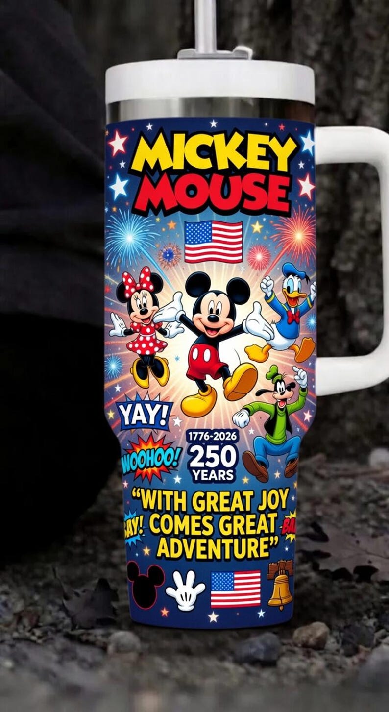 May include: A white-handled tumbler featuring Mickey Mouse and friends against a blue background with fireworks and stars. The tumbler celebrates 250 years with the text "Mickey Mouse", "Yay!", "Woohoo!", and "With great joy comes great adventure."