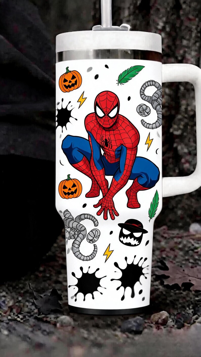 May include: A white stainless steel tumbler with a handle and lid featuring a graphic of Spider-Man in a crouching pose. The design includes orange jack-o'-lanterns, green feathers, yellow lightning bolts, black ink splatters, and gray tentacles.