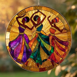 May include: Stained glass suncatcher featuring three dancing figures in colorful gowns. The figures are silhouetted against a golden sunburst design. The dresses are shades of purple, green, and orange. A decorative piece for windows or walls.