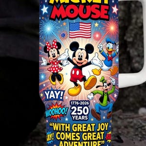 May include: A white-handled tumbler featuring Mickey Mouse and friends against a blue background with fireworks and stars. The tumbler celebrates 250 years with the text "Mickey Mouse", "Yay!", "Woohoo!", and "With great joy comes great adventure."