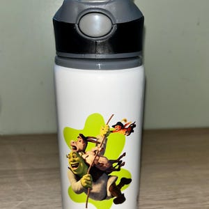 Könnte beinhalten: Weiße Wasserflasche mit einem schwarzen und grauen Deckel. Die Flasche zeigt eine grün-gelbe Grafik von Shrek, Esel und anderen Charakteren. Der Name "NOAH" ist in Blau unter der Grafik aufgedruckt.