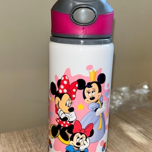 Op de afbeelding: Witte waterfles met een grijze en roze deksel. De fles heeft een kleurrijke afbeelding van Minnie Mouse en vrienden. De naam "LIV" is in paarse letters op de bodem van de fles gedrukt.