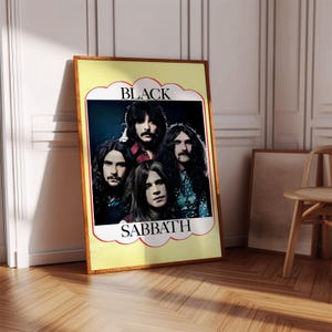 May include: A framed poster of the band Black Sabbath. The poster has a yellow background with the band's name in a white and red decorative banner. The band members are in the center of the poster, with long hair and dark clothing.