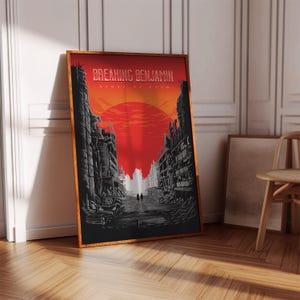 May include: A rectangular poster in a wooden frame featuring a graphic illustration of a post-apocalyptic city street under a large red sun. The text reads Breaking Benjamin and Ashes of Eden. The scene includes ruined buildings and a car.