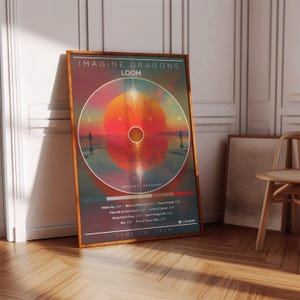 Könnte beinhalten: Gerahmtes Poster mit dem Album "LOOM" von Imagine Dragons. Das Kunstwerk zeigt ein kreisförmiges Design mit einer Sonnenuntergangsszene in Rot-, Orange- und Rosatönen. Das Poster enthält Songtitel und das Datum 28. Juni 2024.