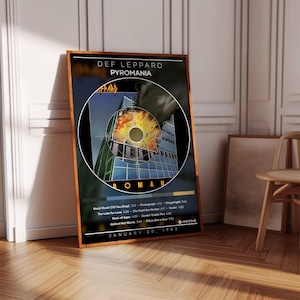 Könnte beinhalten: Ein gerahmtes Poster mit dem Def Leppard-Album "Pyromania". Das Albumcover zeigt ein Gebäude mit einem kreisförmigen Design in der Mitte. Das Poster enthält den Albumtitel, den Bandnamen und die Titelliste. Das Datum "20. Januar 1983" ist ebenfalls zu sehen.