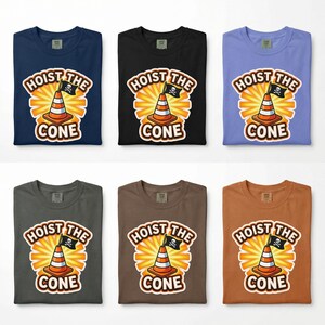 May include: Six t-shirts in various colors, including navy blue, black, and brown. Each shirt features a graphic of a traffic cone with a pirate flag and the words "HOIST THE CONE". The design is set against a radiating sunburst.
