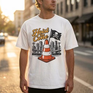 Pu&ograve; includere: T-shirt bianca con grafica raffigurante un cono stradale, una bandiera pirata e uno skyline cittadino. La scritta "Hoist the Cone" &egrave; arancione e gialla. Un capo di abbigliamento casual.