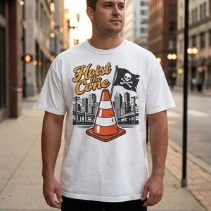 Pu&ograve; includere: T-shirt bianca con la scritta "Hoist the Cone" in giallo e arancione. La grafica include un cono stradale, una bandiera pirata con teschio e ossa incrociate e uno skyline. La maglietta &egrave; a maniche corte.