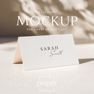 May include: A folded white card with the name "Sarah Smith" printed on it. The card is a mockup, with the text "3.5x2 CARD MOCKUP" at the top. The card is on a white surface with a shadow.