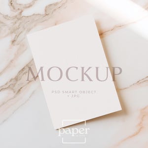 Può includere: Una carta bianca rettangolare tipo mockup con una superficie in carta testurizzata. La carta mostra il testo MOCKUP, PSD SMART OBJECT + JPG e il logo paper in mind. La carta è posizionata ad angolo, mostrando un design pulito e professionale.