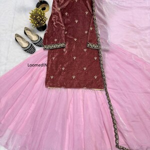 May include: A maroon velvet tunic with gold embroidery and long sleeves is paired with a light pink skirt and a matching sheer scarf. The outfit is displayed with black and white patterned flats and decorative accents.