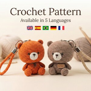 Puede incluir: Dos llaveros de oso de ganchillo, uno naranja y otro marrón, con caras blancas y pequeños llaveros de metal. La imagen incluye el texto "Crochet Pattern" y "Available in 5 Languages".