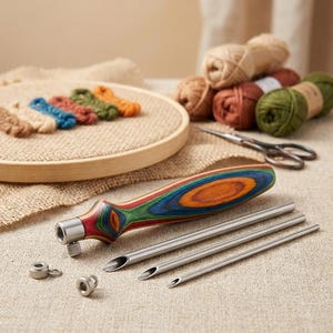 May include: A punch needle tool with a multi-coloured laminated wood handle, three interchangeable stainless steel needle tips of varying diameters, and two small metal locking nuts, arranged on a textured fabric surface.