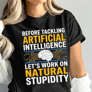 Può includere: T-shirt nero con la scritta "BEFORE TACKLING ARTIFICIAL INTELLIGENCE LET'S WORK ON NATURAL STUPIDITY" in bianco e giallo. Il design include un cervello e linee di circuito stampato.