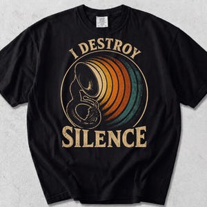 Peut inclure: Un t-shirt noir à manches courtes arborant un tuba en laiton au centre d'un motif circulaire composé d'anneaux orange, jaunes et bleu sarcelle. Le texte "I DESTROY SILENCE" est imprimé dans une police serif beige vieillie au-dessus et en dessous.