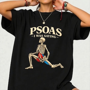 May include: Black t-shirt with the text "PSOAS - I WAS SAYING" above a skeletal figure in a stretching pose. The skeleton's muscles are highlighted in red and blue. The shirt is a casual wear item.