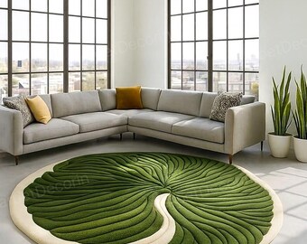 May include: A round, green and cream-colored rug with a leaf design. The rug is placed in a modern living room with a gray sectional sofa and large windows. The rug's diameter is approximately 7 feet.