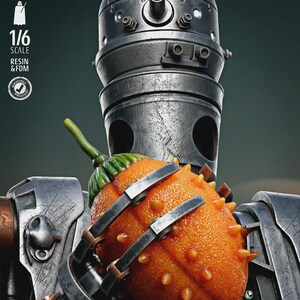 May include: A detailed, metallic robot figure holding a vibrant orange kiwano fruit. The robot has a cylindrical head and mechanical arms. The fruit is covered in small, orange spikes. The image includes text that reads "TESTED PRESUPPORTED" and "1/6 SCALE".