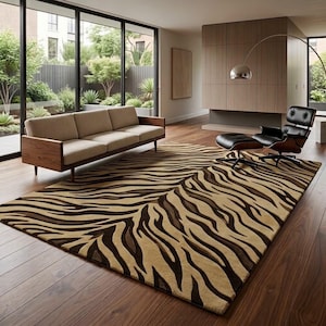 May include: A rectangular area rug featuring a repeating tiger stripe pattern in shades of tan, dark brown, and black. The rug is laid flat on a dark wood floor, covering a large portion of the floor space in front of a sofa and lounge chair.