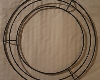 May include: A black metal wreath frame with three concentric circular rings. The frame is designed for crafting and decorating wreaths, with a sturdy construction and a simple, clean design. The frame is suitable for various craft projects.