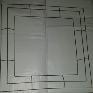 Puede incluir: Un marco de corona de metal negro con forma cuadrada y un diseño decorativo. El marco está hecho de alambre y tiene un aspecto simple y moderno.