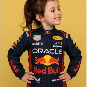 May include: A dark blue racing suit featuring the Oracle Red Bull Racing team branding, including logos for TAG Heuer, Mobil 1, Rauch, Bybit, Honda, and Castore. The suit displays the Red Bull emblem, the name Max, and a small Dutch flag on the chest.