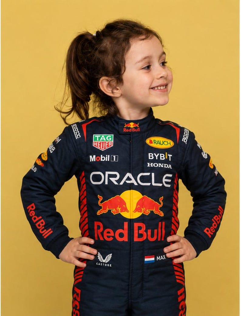 May include: A dark blue racing suit featuring the Oracle Red Bull Racing team branding, including logos for TAG Heuer, Mobil 1, Rauch, Bybit, Honda, and Castore. The suit displays the Red Bull emblem, the name Max, and a small Dutch flag on the chest.