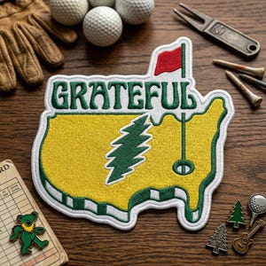 May include: Embroidered patch in the shape of the United States with the word "Grateful" in green. The patch features a green tree and a red flag. Golf balls, tees, and a divot repair tool are also visible.