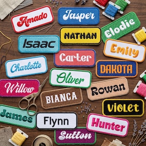 May include: A collection of embroidered name patches in various colors, including red, blue, and green. Each patch features a different name in a contrasting color, such as "Amado," "Jasper," and "Elodie." The patches are rectangular with a white border.