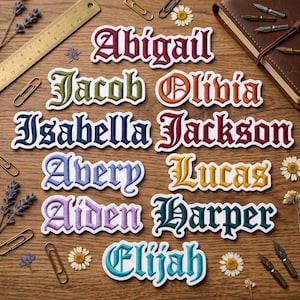 May include: Embroidered name patches in various colors, including burgundy, green, and blue, arranged on a wooden surface. Names include Abigail, Jacob, Olivia, Isabella, Jackson, Avery, Lucas, Aiden, Harper, and Elijah. Decorative elements include paperclips and flowers.