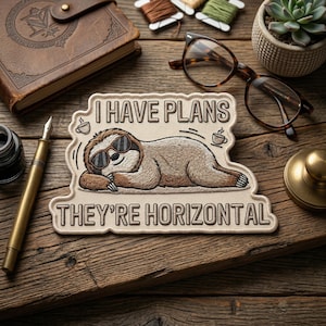 May include: Embroidered patch featuring a sloth wearing sunglasses, with the text "I HAVE PLANS THEY'RE HORIZONTAL". The sloth is lying down, with coffee cup icons on either side. The patch is beige with brown and black details.
