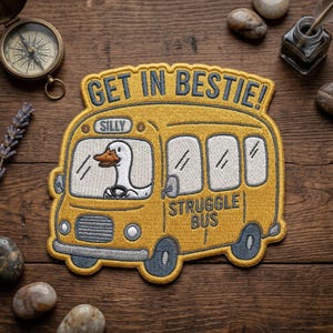 May include: Embroidered yellow patch featuring a cartoon school bus with a goose driving. The text "GET IN BESTIE!" arches above the bus, and "STRUGGLE BUS" is below. The word "SILLY" is above the goose.