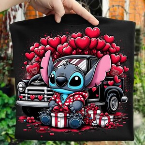 May include: Black t-shirt featuring a cartoon character in a red and white heart-patterned hoodie, sitting in front of a black truck. Red hearts and gifts surround the character, with the text "Happy Valentine's Day".
