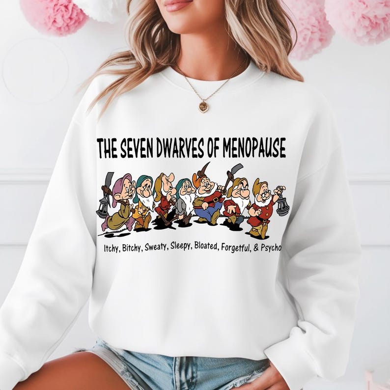 May include: White sweatshirt featuring a graphic of the Seven Dwarves with the text "THE SEVEN DWARVES OF MENOPAUSE" above them. Below the dwarves are the words "Itchy, Bitchy, Sweaty, Sleepy, Bloated, Forgetful, & Psycho."