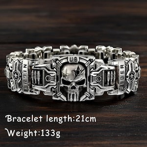 Könnte beinhalten: Silberfarbenes Armband mit Totenkopf-Design und den Schriftzügen "US" und "NIGHT RIDER". Das Armband ist 21 cm lang und wiegt 133 g.