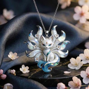 May include: A silver-toned pendant necklace featuring a nine-tailed fox design. The fox is crafted with white iridescent enamel, blue accents on the tail tips, and small white flower embellishments. The pendant hangs from a delicate silver chain.